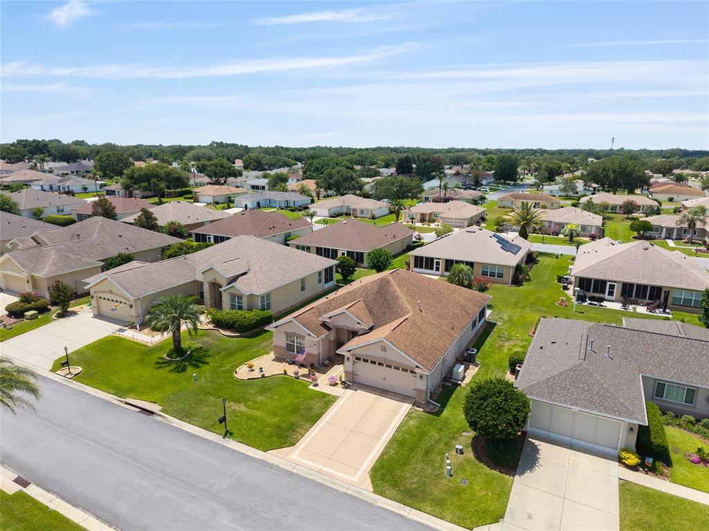 An aerial view shows a suburban neighborhood with single-family homes, paved driveways, and green lawns — 8716 SE 136TH PLACE, SUMMERFIELD, FL