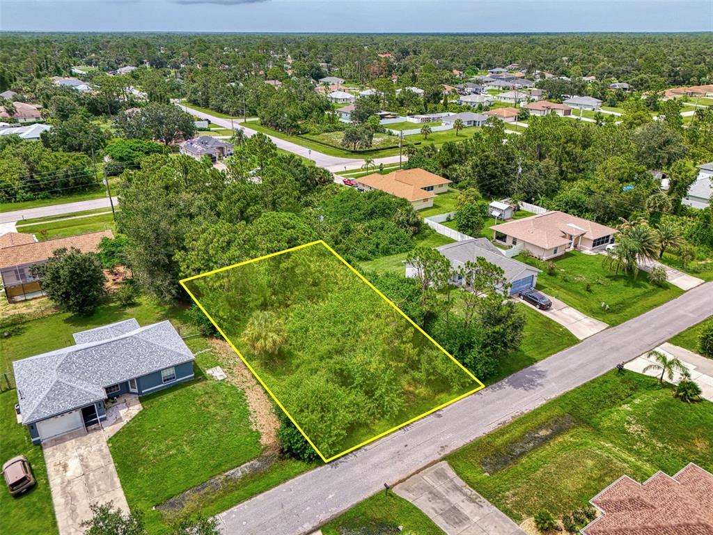 An aerial view shows a vacant, rectangular residential lot outlined in yellow between two houses — DUAR TERRACE, NORTH PORT, FL