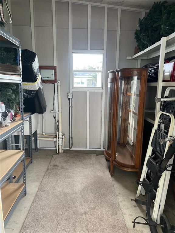 A storage shed interior features metal shelving, a wooden display cabinet, and a small window — 12 THATCH PALM STREET W, LARGO, FL