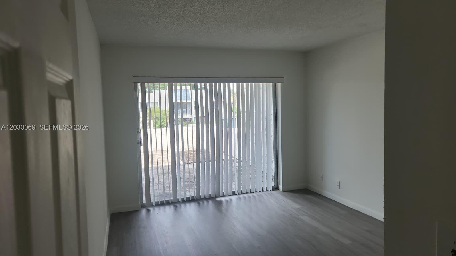A room with gray wood-look flooring, white walls, and a sliding glass door with blinds — 1817 NW 58th Ave # 22, Lauderhill FL 33313, LAUDERHILL, FL