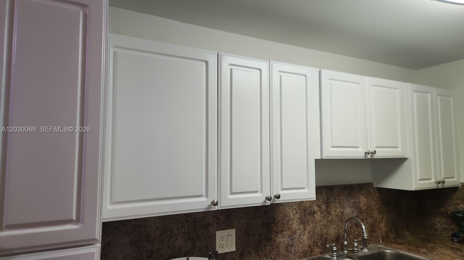 White kitchen cabinets are mounted above a brown speckled countertop and a stainless steel sink — 1817 NW 58th Ave # 22, Lauderhill FL 33313, LAUDERHILL, FL