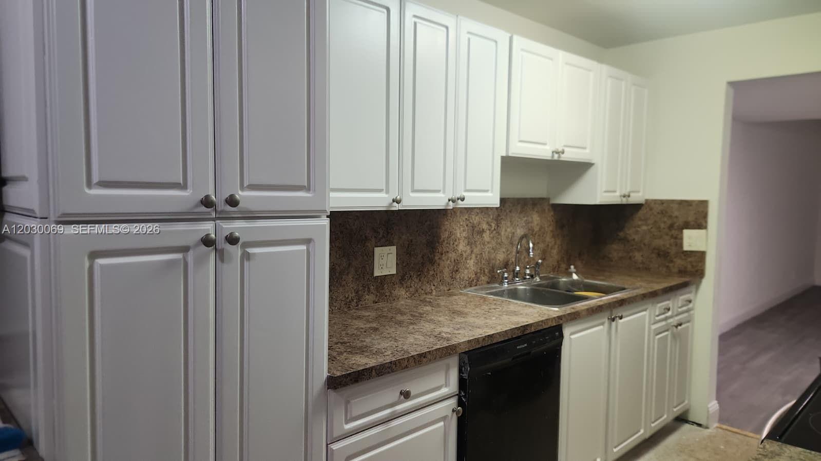 A kitchen features white cabinets, a brown laminate countertop, and a black dishwasher — 1817 NW 58th Ave # 22, Lauderhill FL 33313, LAUDERHILL, FL
