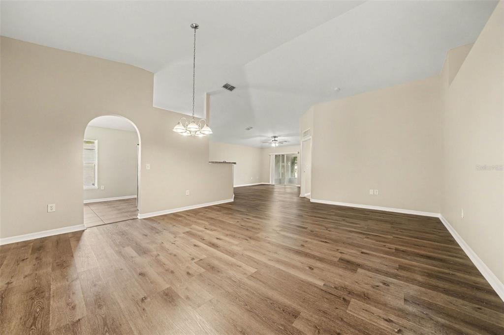 An empty room with light-colored walls, vaulted ceilings, and wood-look flooring — 2208 NICOLLETT WAY, LEESBURG, FL