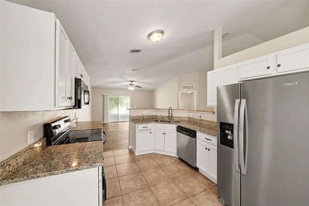 An empty room with wood-look flooring, a ceiling fan, and sliding glass doors to a patio — 2208 NICOLLETT WAY, LEESBURG, FL