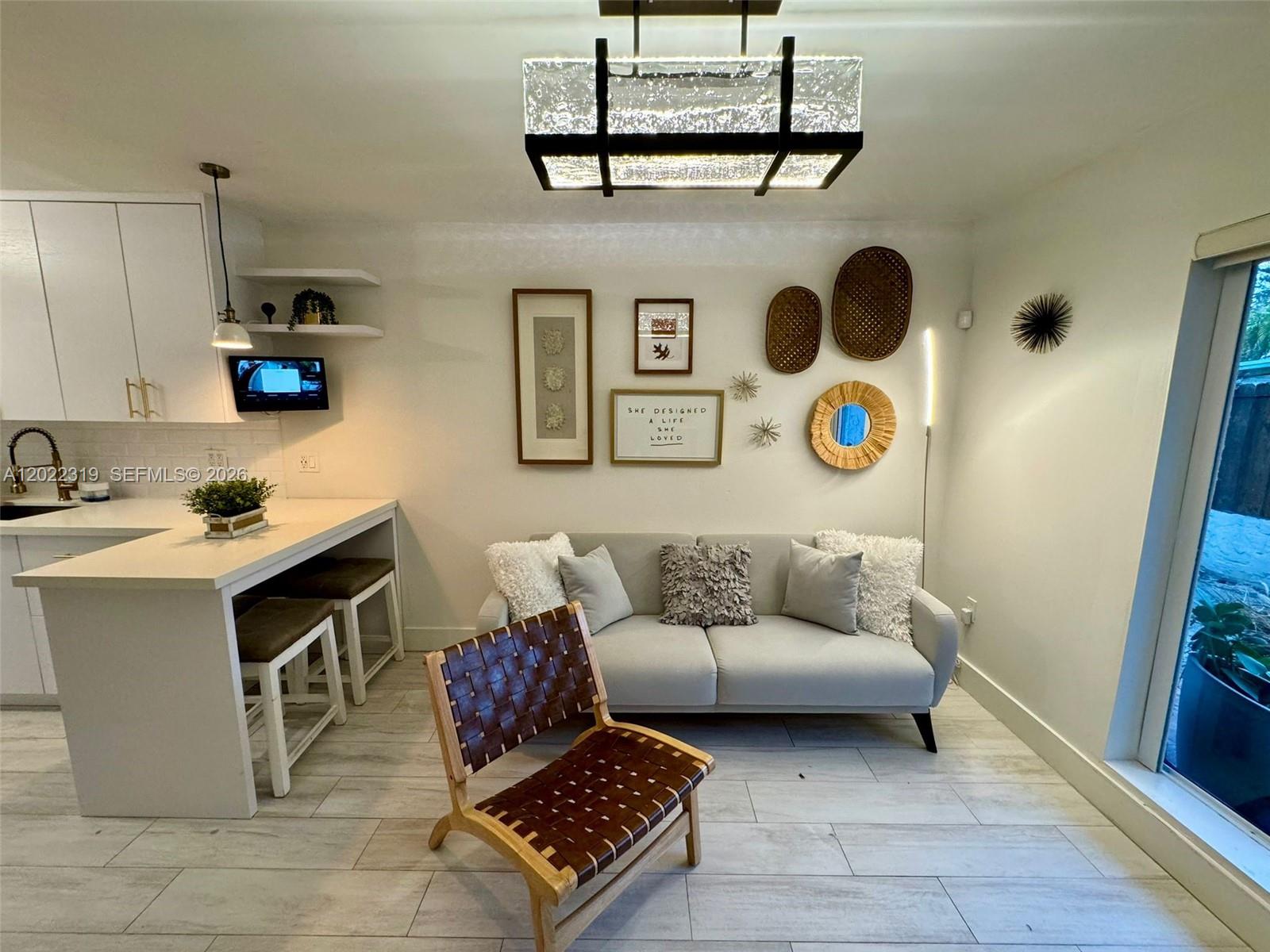 A living room with a sofa, leather accent chair, and an adjacent kitchen breakfast bar — 1121 SW 7th St # 1, Miami FL 33130, MIAMI, FL