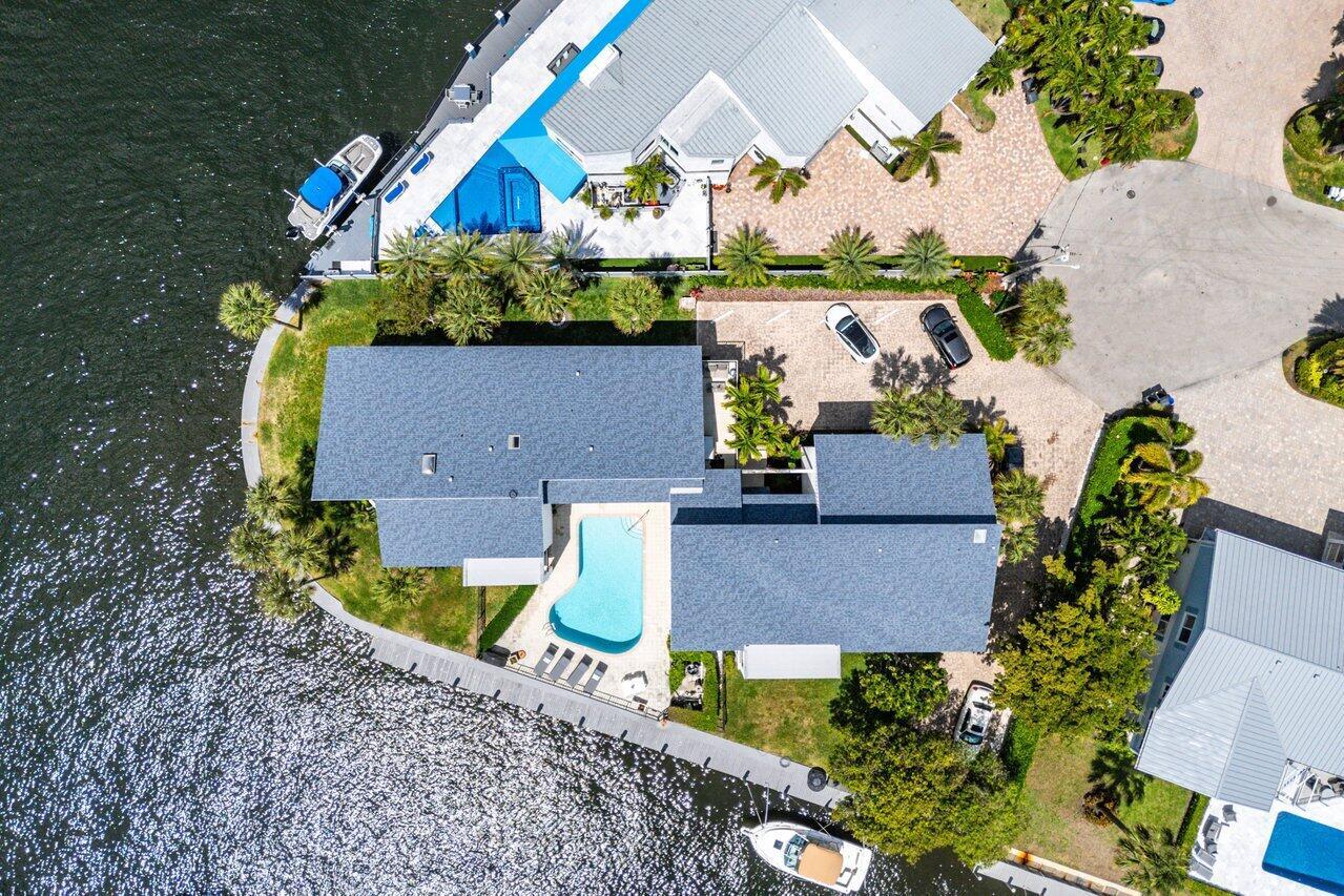 An aerial view shows a waterfront house with a pool, boat dock, and paved driveway — 1102 Highland Beach Drive # 2w, Highland Beach FL 33487, HIGHLAND BEACH, FL