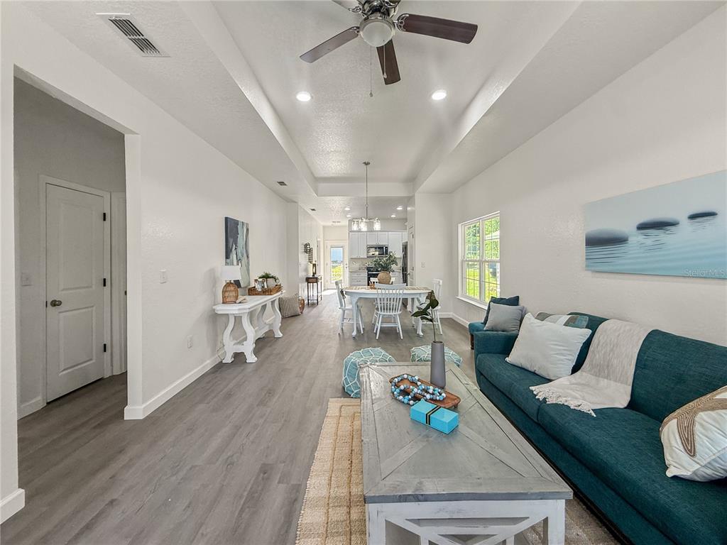 A living room with a teal sofa and coffee table leads to a dining area — 15341 NW 135TH TERRACE, ALACHUA, FL