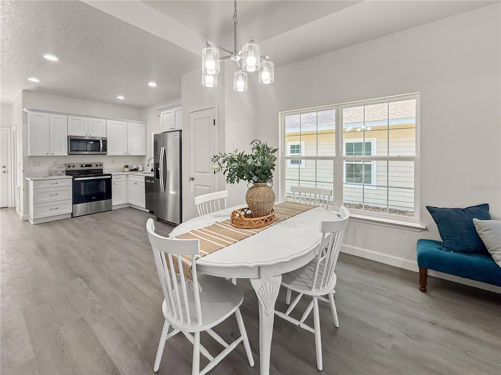 A dining area with a white table and chairs sits adjacent to a modern kitchen — 15341 NW 135TH TERRACE, ALACHUA, FL