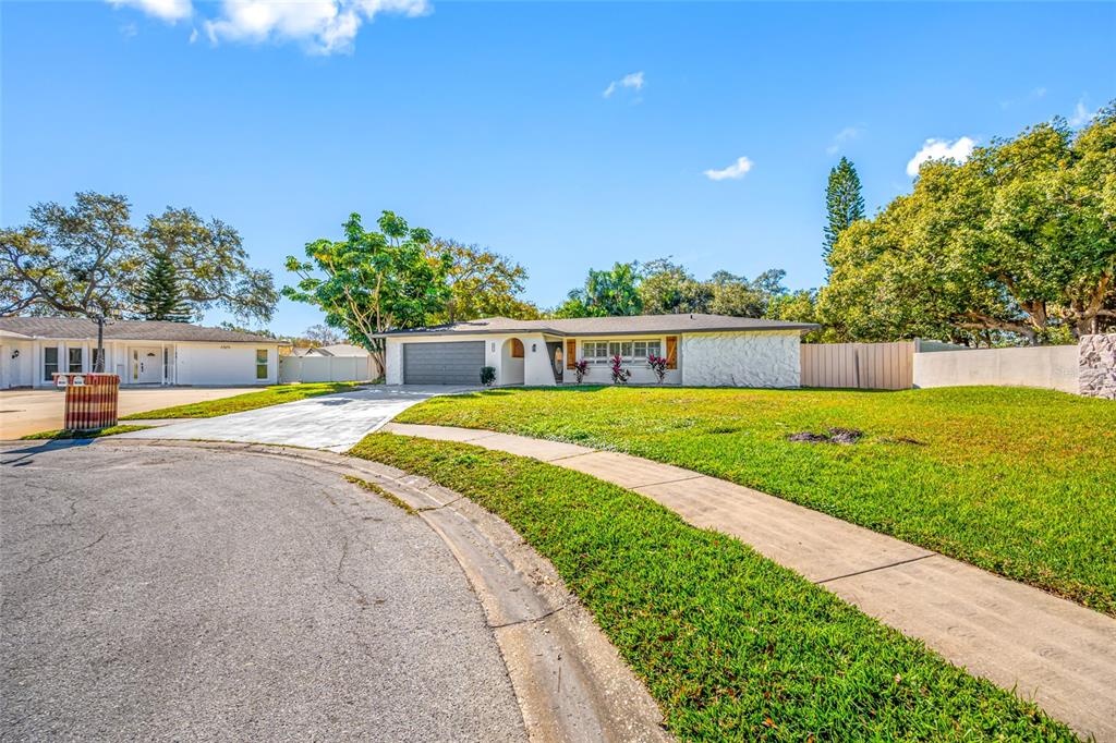 A single-story house with a white stone facade, a gray garage, and a front lawn — 1932 ORO COURT, CLEARWATER, FL