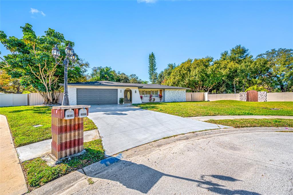 A single-story house with a gray garage, white exterior, and a concrete driveway — 1932 ORO COURT, CLEARWATER, FL