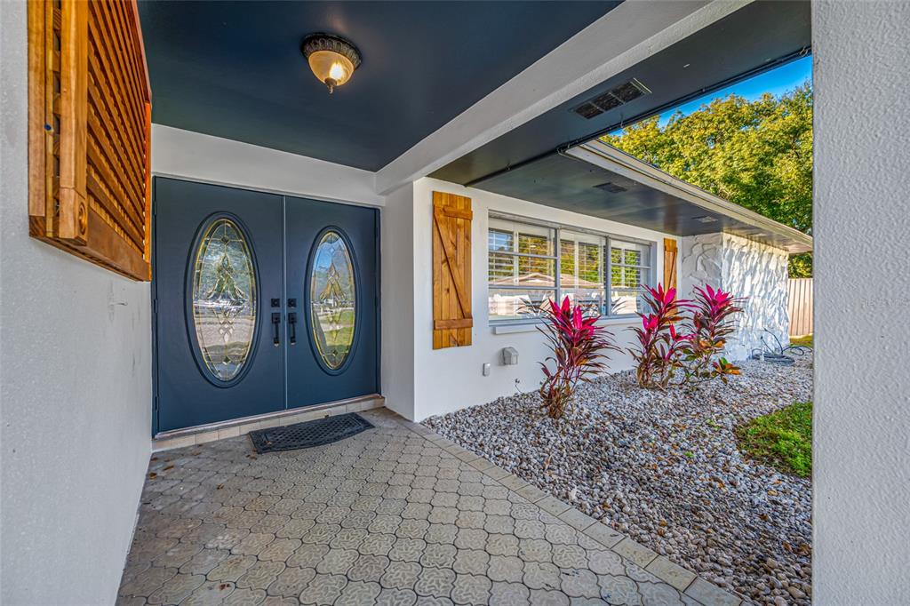 A covered entryway features double doors with oval glass inserts and a stone-paved porch — 1932 ORO COURT, CLEARWATER, FL