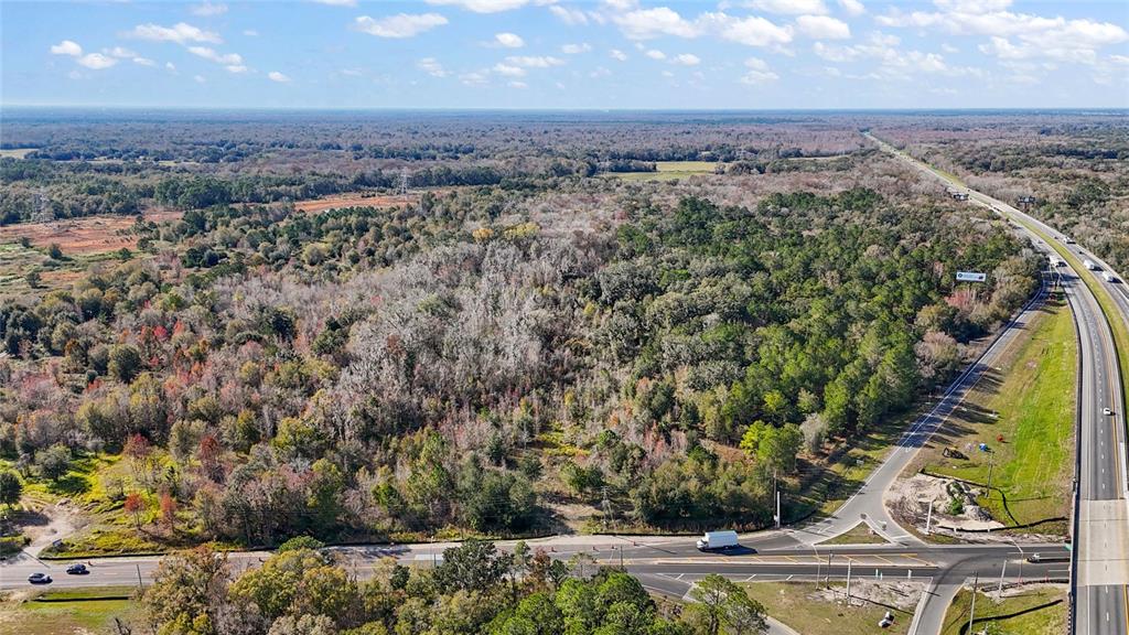 An aerial view shows a large, wooded plot of land adjacent to a highway intersection — HWY 301 / MAIN STREET, WILDWOOD, FL