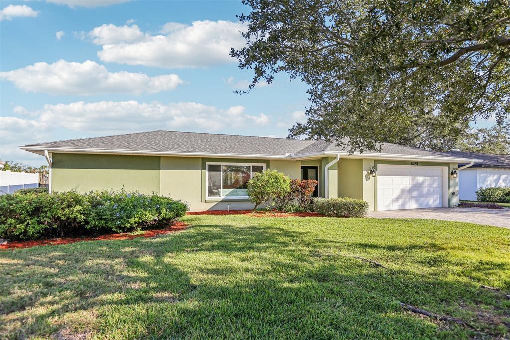 A single-story house with a light green exterior, a two-car garage, and a large lawn — 6251 18TH STREET NE, ST PETERSBURG, FL