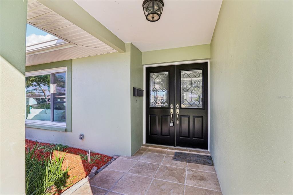 A covered entryway features a tiled porch, light green walls, and black double front doors — 6251 18TH STREET NE, ST PETERSBURG, FL