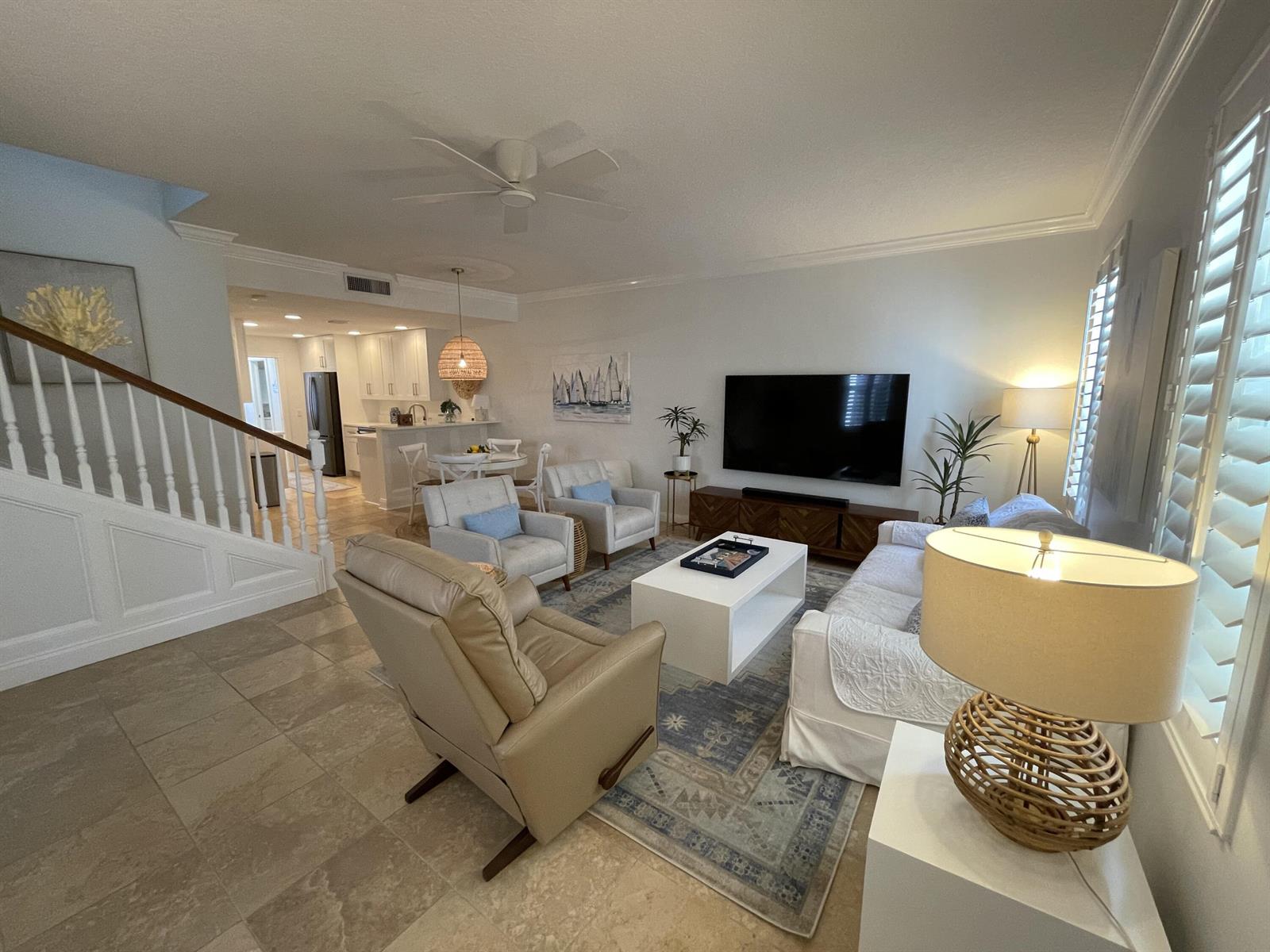 A living room features tile flooring, a white sofa, armchairs, and a wall-mounted television — 2857 E Community Drive, Jupiter FL 33458, JUPITER, FL