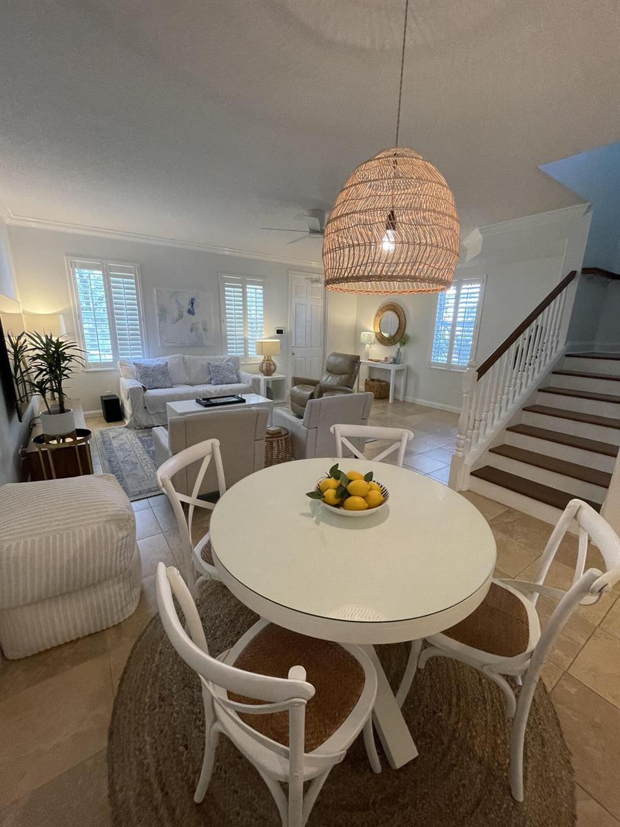 A dining area with a round white table and woven chairs sits before a living room — 2857 E Community Drive, Jupiter FL 33458, JUPITER, FL