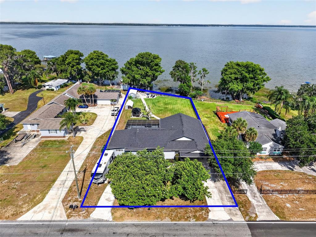 An aerial view shows a waterfront house with a large backyard and a driveway — 32739 LAKE EUSTIS DRIVE, TAVARES, FL