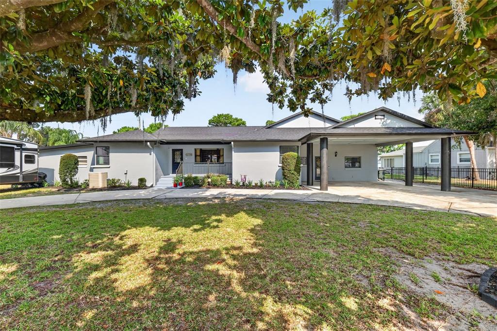 A gray single-story house features a large front lawn, a carport, and a mature tree — 32739 LAKE EUSTIS DRIVE, TAVARES, FL
