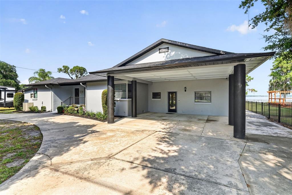 A single-story house with a large carport, gray exterior walls, and a concrete driveway — 32739 LAKE EUSTIS DRIVE, TAVARES, FL