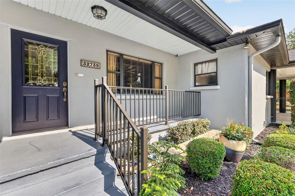 A dark blue front door with a glass insert sits beside a window and railing — 32739 LAKE EUSTIS DRIVE, TAVARES, FL