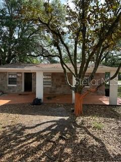 A single-story stone house features a covered front porch and a large tree in front — 7731 UDINE AVENUE, ORLANDO, FL