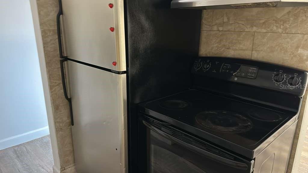 A stainless steel refrigerator stands next to a black electric stove in a kitchen — 7731 UDINE AVENUE, ORLANDO, FL
