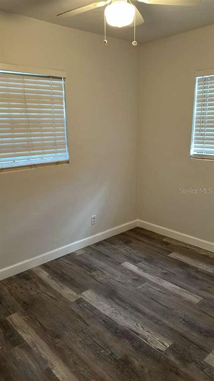 An empty bedroom features light-colored walls, wood-look flooring, two windows with blinds, and a ceiling fan — 7731 UDINE AVENUE, ORLANDO, FL