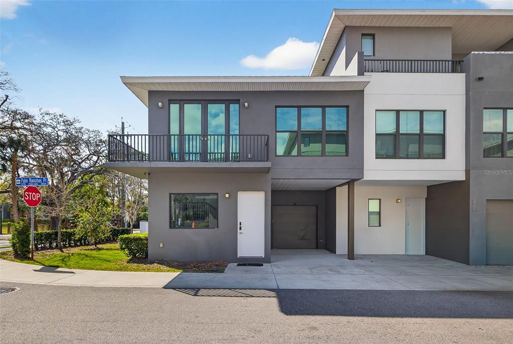 A modern two-story townhouse with a gray and white exterior, balcony, and attached garage — 8706 PALM RANCHES PLACE, TAMPA, FL