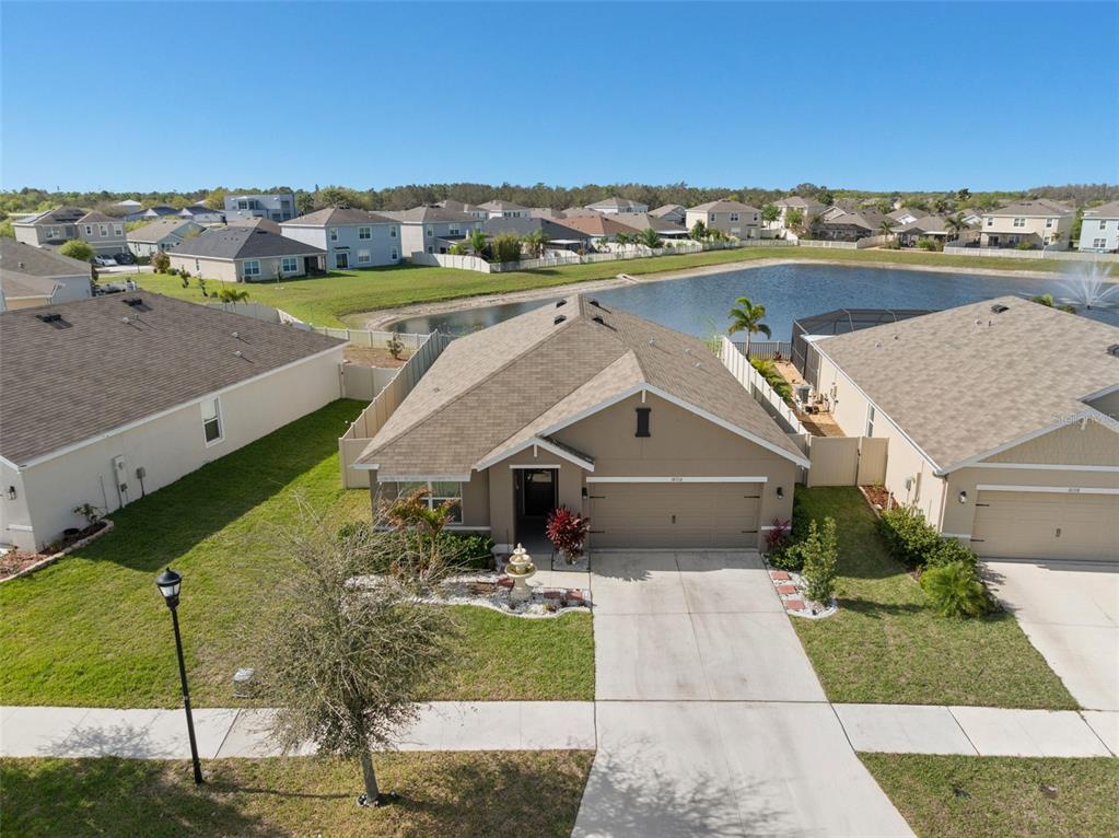 An aerial view shows a single-story house with a tan exterior and a concrete driveway — 16316 LITTLE GARDEN DRIVE, WIMAUMA, FL
