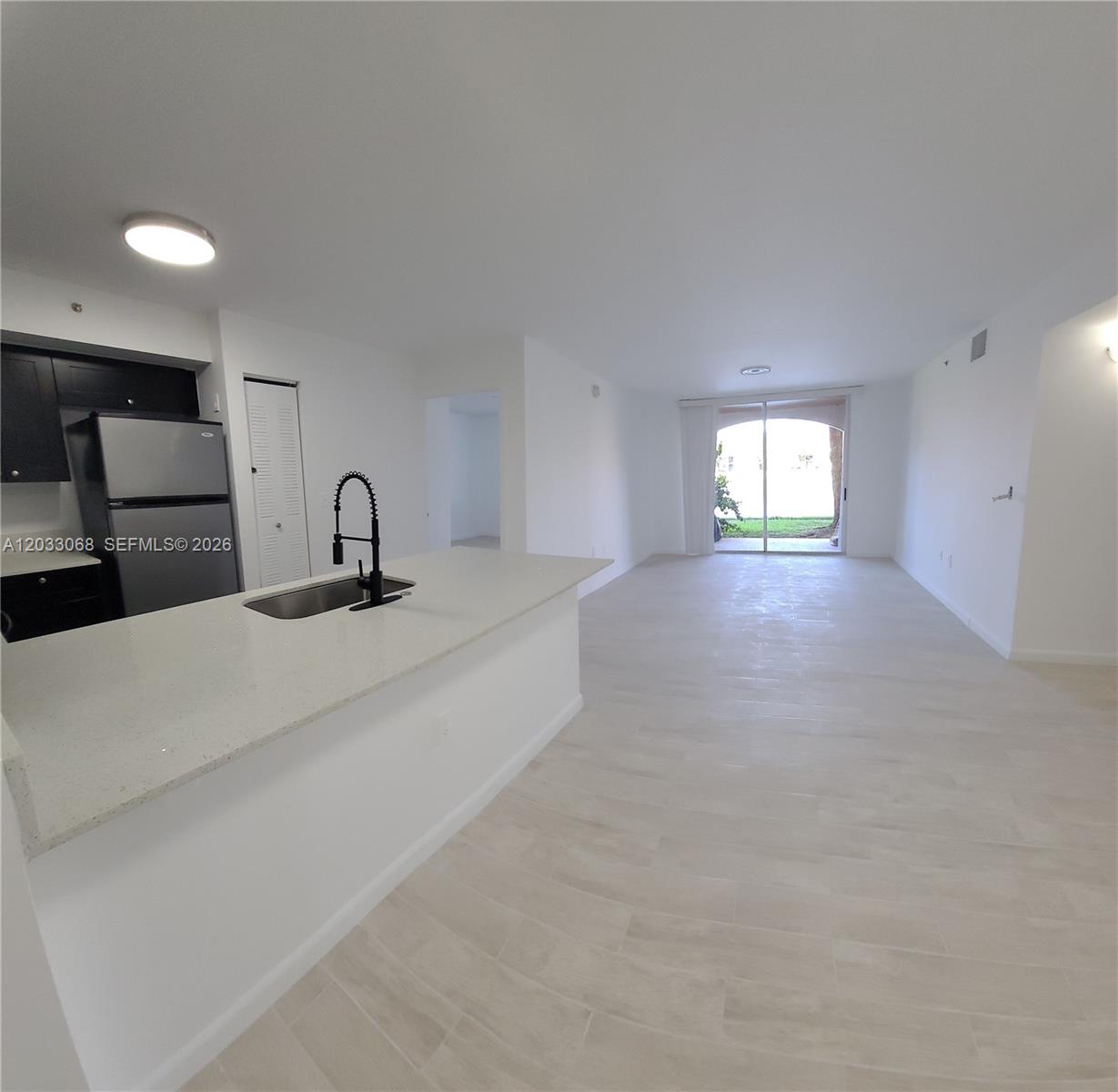 A kitchen with a white island and dark cabinets opens into a spacious living area — 2021 Renaissance Blvd # 104, Miramar FL 33025, MIRAMAR, FL