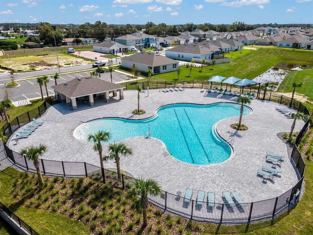 An aerial view of a community swimming pool with a pavilion and surrounding lounge chairs — 3886 WHITNEY WAY, HAINES CITY, FL