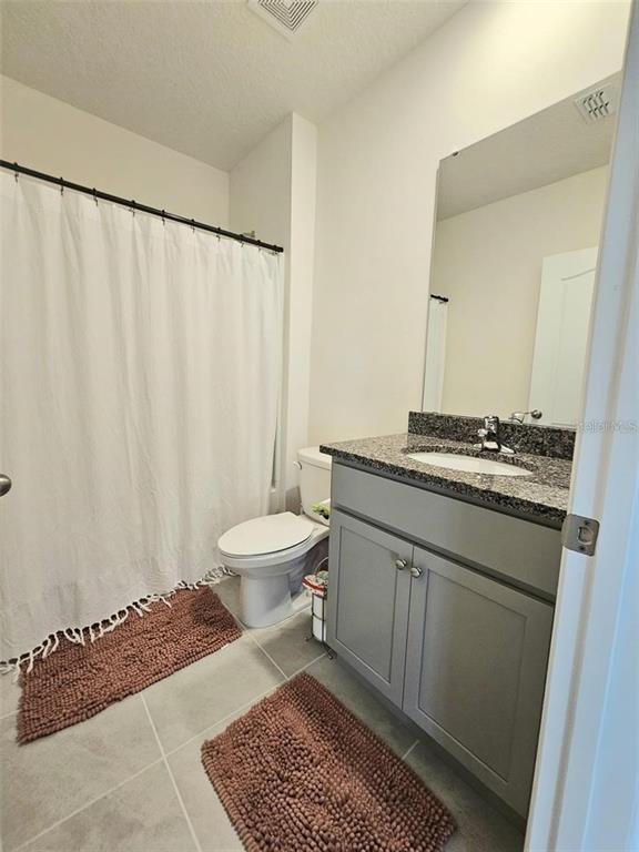 A bathroom features a gray vanity with a granite countertop, a toilet, and a shower curtain — 3886 WHITNEY WAY, HAINES CITY, FL