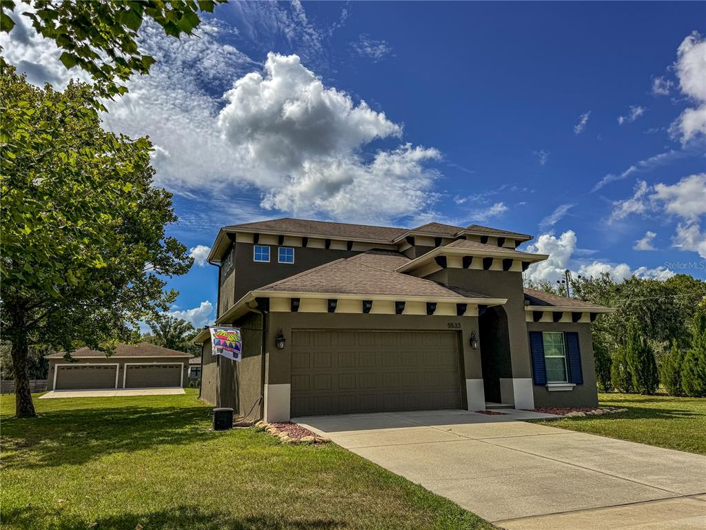 A two-story house with a brown stucco exterior, a two-car garage, and a detached garage — 5533 TOWER ROAD, LAND O LAKES, FL