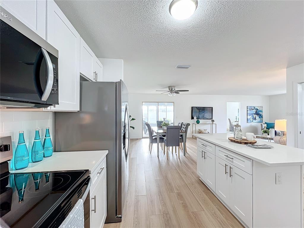 A modern kitchen with white cabinets and stainless steel appliances overlooks a dining area — 3932 ASHWOOD LANE UNIT 42, SARASOTA, FL