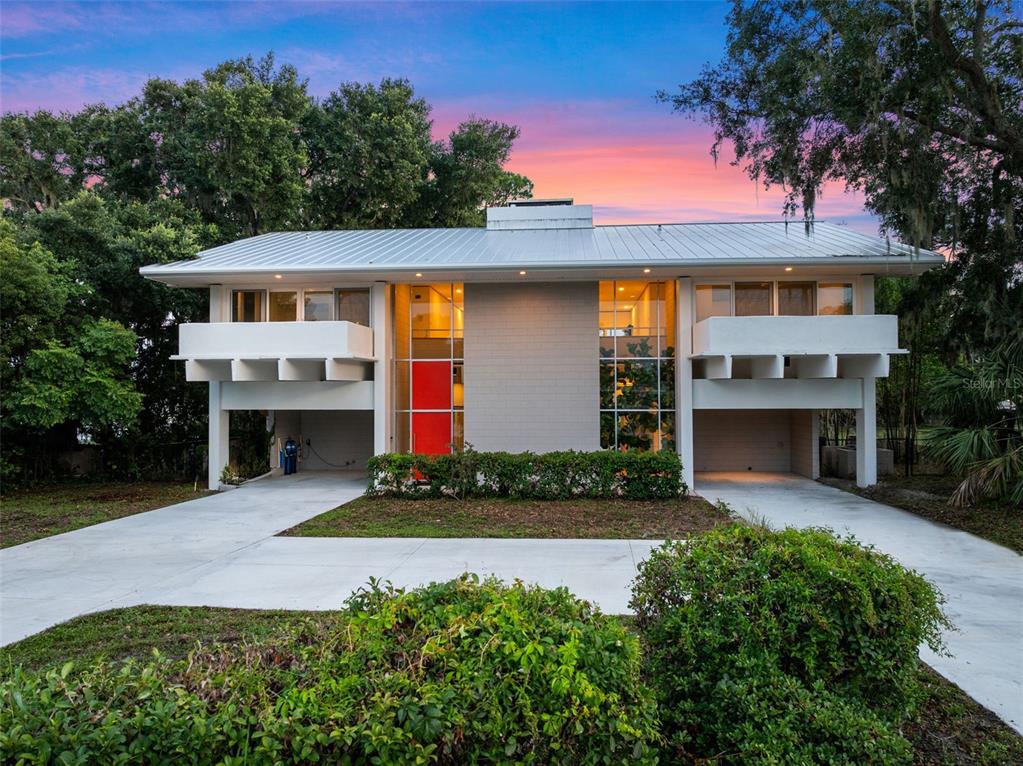A two-story house with a flat roof, solar panels, and a large grassy backyard — 1540 N LAKE MIRROR DRIVE NW, WINTER HAVEN, FL
