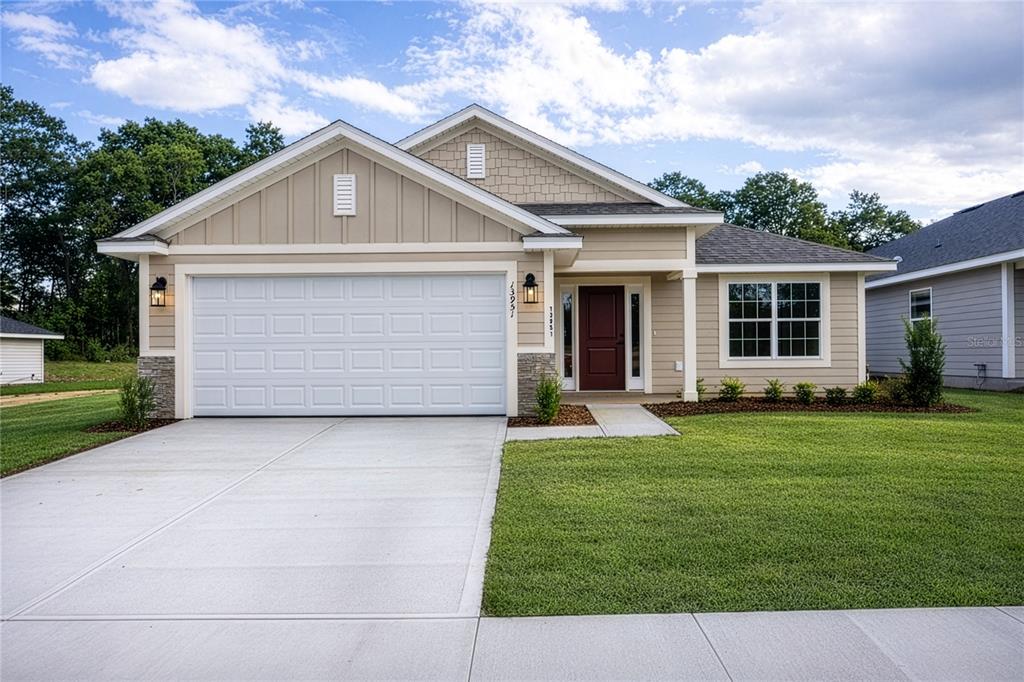A single-story suburban house with a tan exterior, white garage door, and a red front door — 16913 NW 176TH WAY, ALACHUA, FL