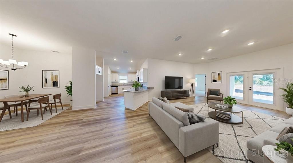 This open-concept living and dining area features wood-look flooring, white walls, and virtual staging — 16913 NW 176TH WAY, ALACHUA, FL