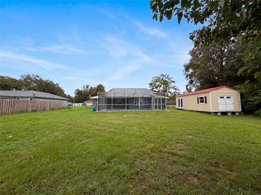 A backyard features a screened-in pool, a detached shed, and a wooden fence — 38 HEMLOCK TERRACE PASS, OCALA, FL