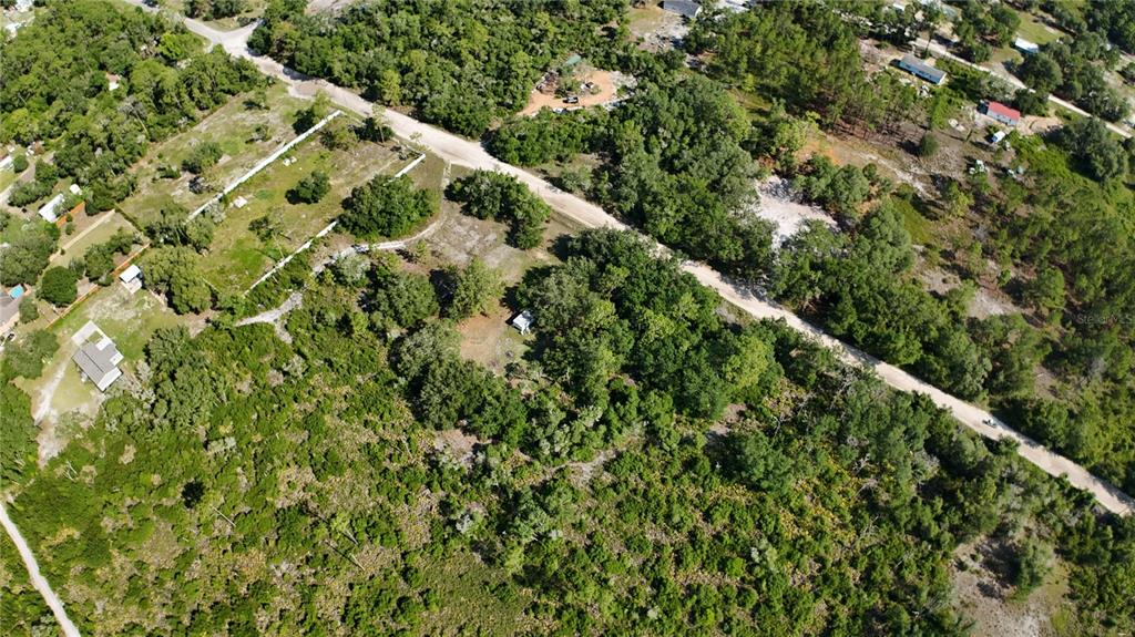 An aerial view shows a wooded lot with a small structure and dirt roads — XX SW 156TH PLACE, DUNNELLON, FL