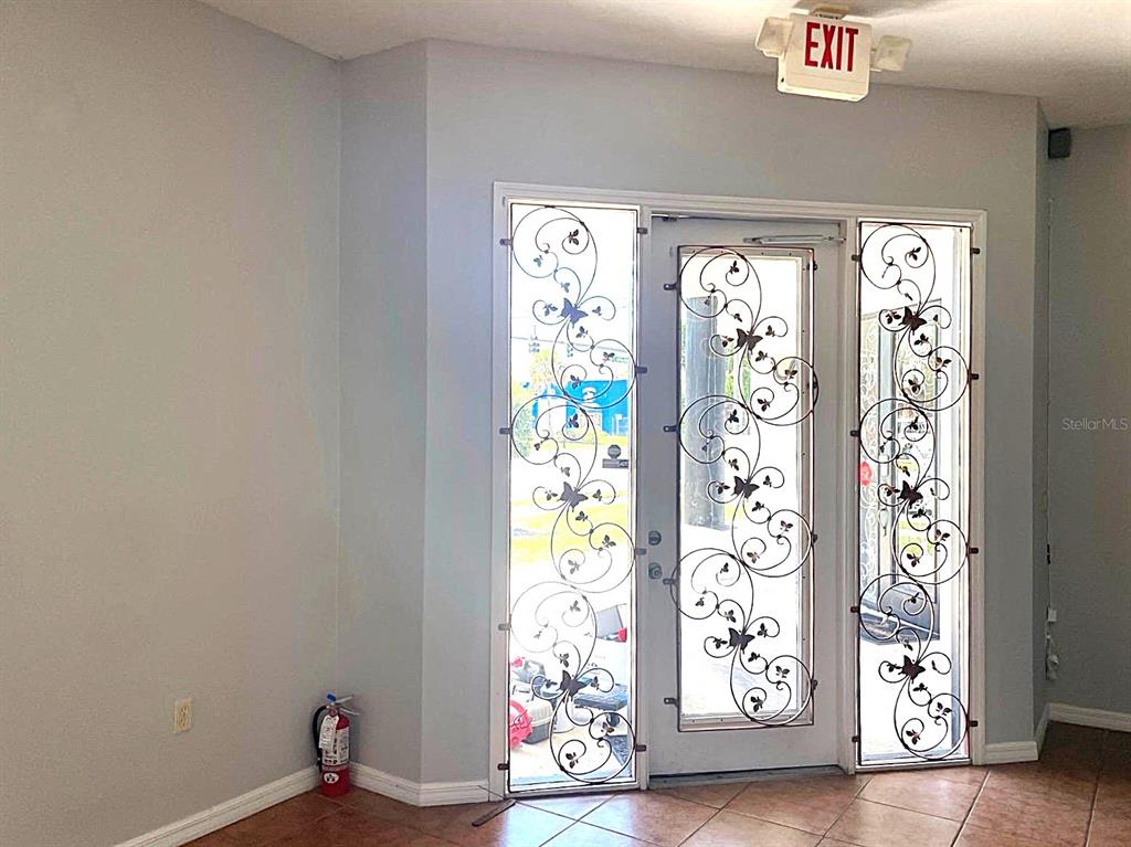 An interior entryway features a glass door with decorative metal scrollwork and an exit sign — 3001 MICHIGAN AVENUE UNIT B, KISSIMMEE, FL