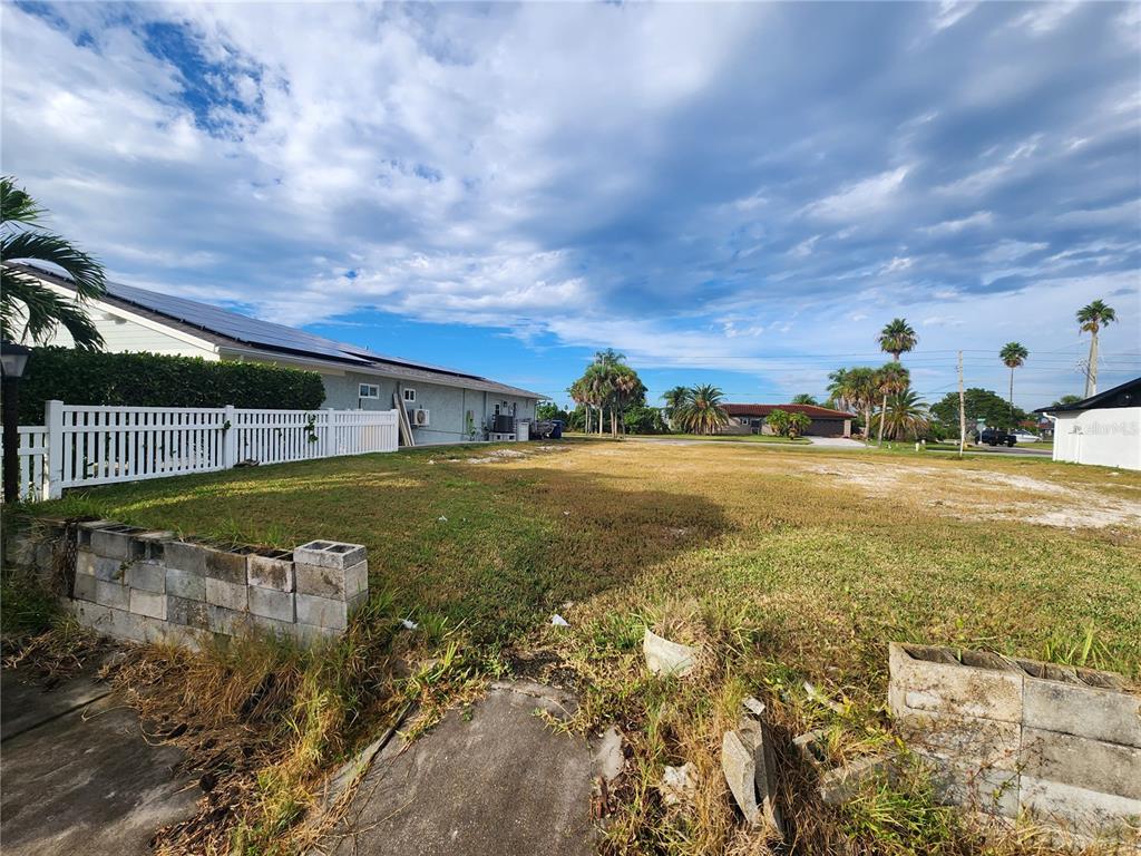 A vacant, grassy lot sits next to a white house with a white picket fence — 3532 FLORAMAR TERRACE, NEW PORT RICHEY, FL