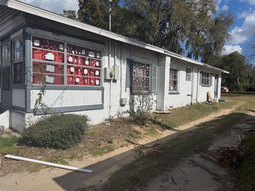 A single-story white brick house with red curtains and a dirt driveway — 11751 N WILLIAMS STREET, DUNNELLON, FL