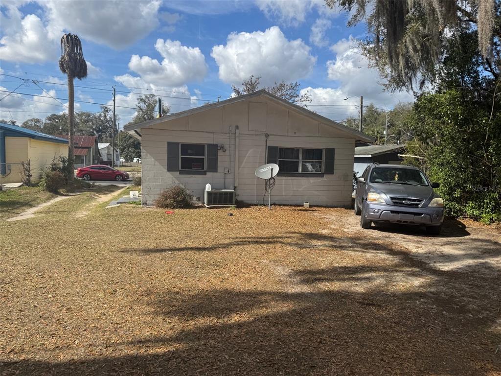 A single-story concrete block house with a gravel driveway and a parked SUV — 11751 N WILLIAMS STREET, DUNNELLON, FL