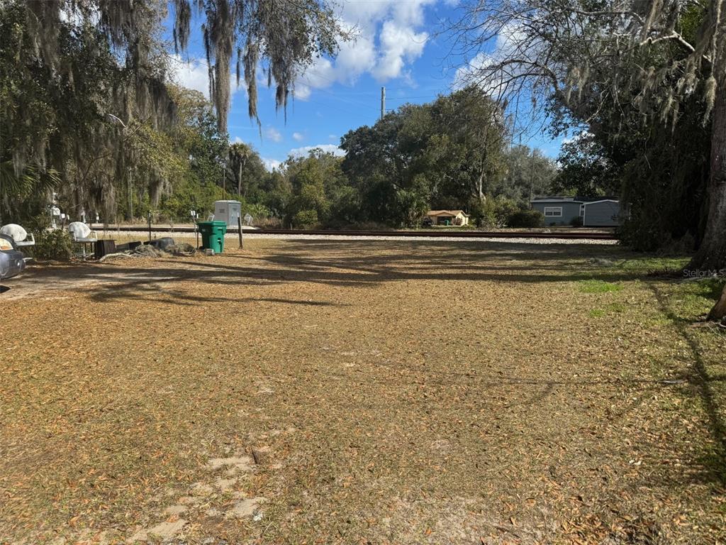 A vacant, grassy lot features a railroad track running across the background — 11751 N WILLIAMS STREET, DUNNELLON, FL