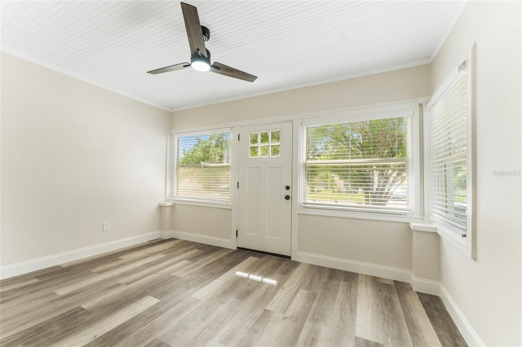 A sunroom features light wood-look flooring, white walls, a ceiling fan, and multiple windows — 1922 23RD STREET S, ST PETERSBURG, FL