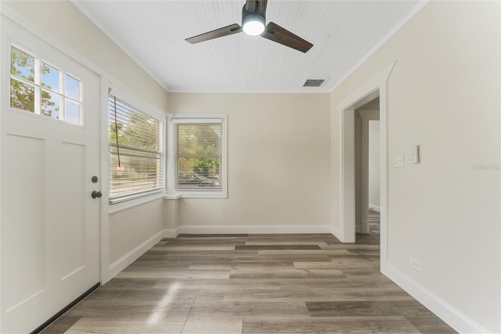 An empty room features wood-look flooring, a ceiling fan, and windows with white blinds — 1922 23RD STREET S, ST PETERSBURG, FL