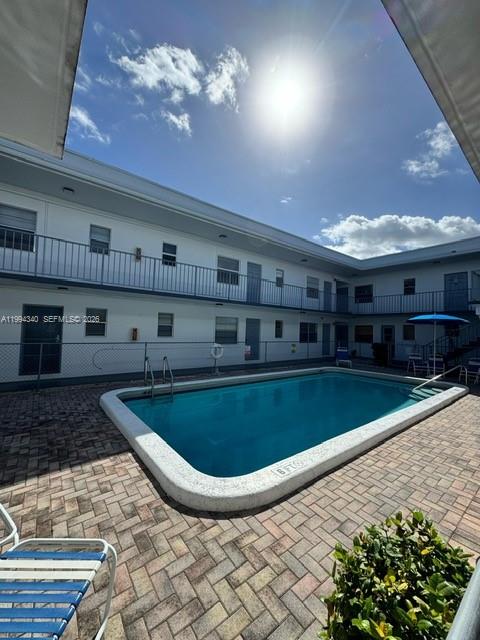 A rectangular swimming pool sits in a paved courtyard surrounded by a two-story apartment building — 30 SE 4th Ave # 109, Hallandale Beach FL 33009, HALLANDALE BEACH, FL