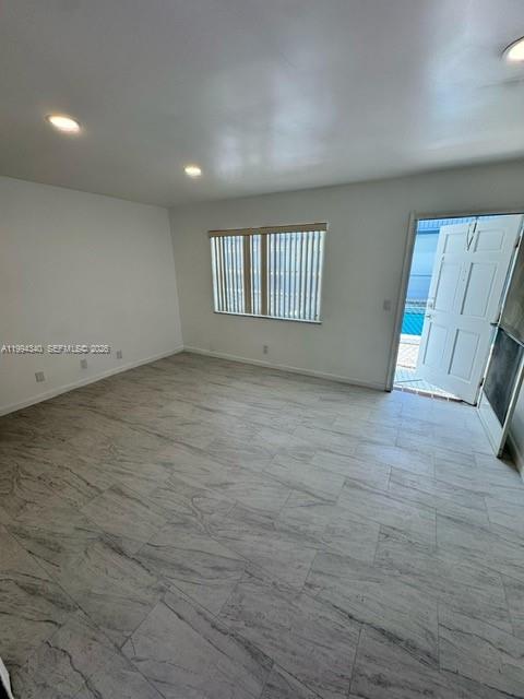 An empty room features light-colored marble-patterned tile flooring, white walls, and a door leading outside — 30 SE 4th Ave # 109, Hallandale Beach FL 33009, HALLANDALE BEACH, FL