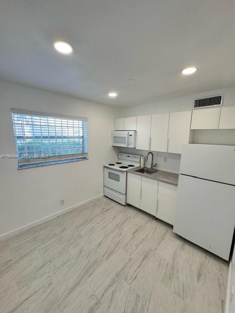 A kitchen features white cabinets, a white stove, a white refrigerator, and light-colored flooring — 30 SE 4th Ave # 109, Hallandale Beach FL 33009, HALLANDALE BEACH, FL