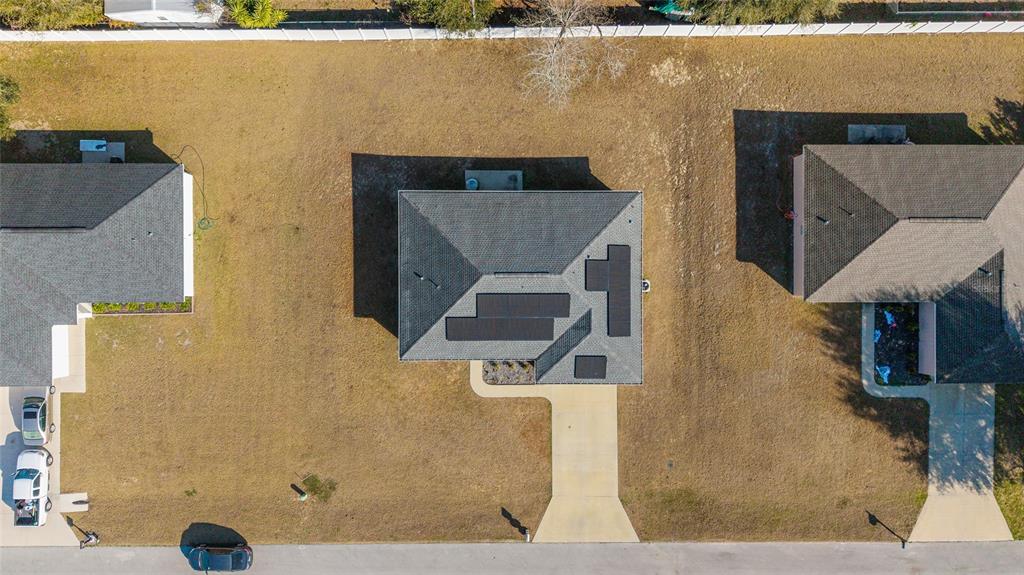 An aerial view shows a single-family home with solar panels on the roof and driveway — 1803 NE 161ST PLACE, CITRA, FL